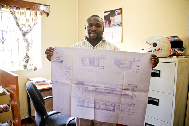 Nyeko Denis, a S4S engineering assistant with the plans for a building project.