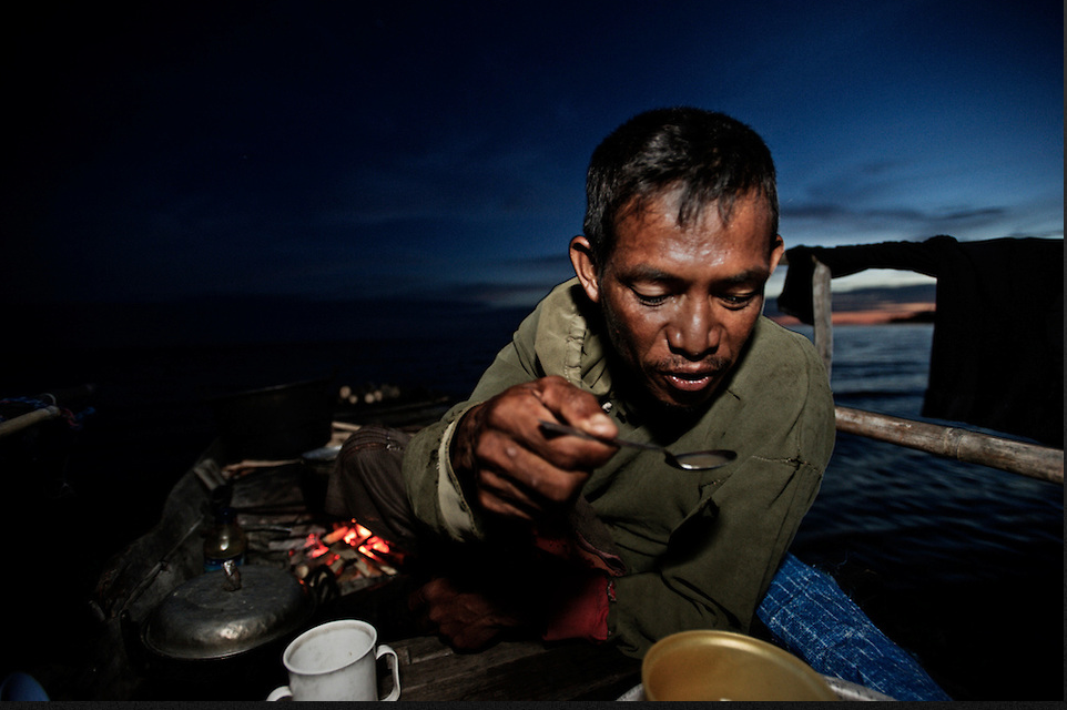 A Bajau Laut native eats dinner on his lepa lepa
