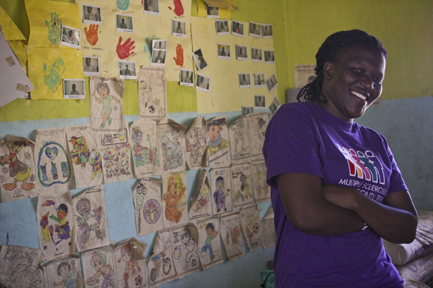 Collines poses by the artwork of the 40 children served at the Hope for Humans nodding syndrome center in northern Uganda