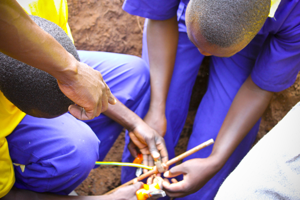 Students learn how to ground electrical wires from a building.